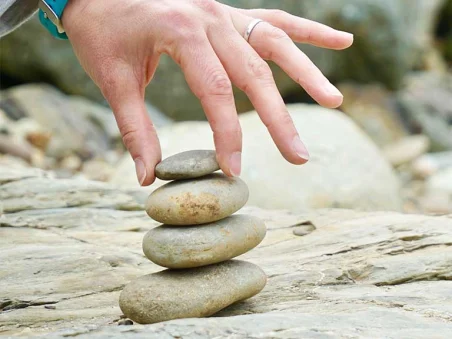 A hand placing small stones in a tiered stack